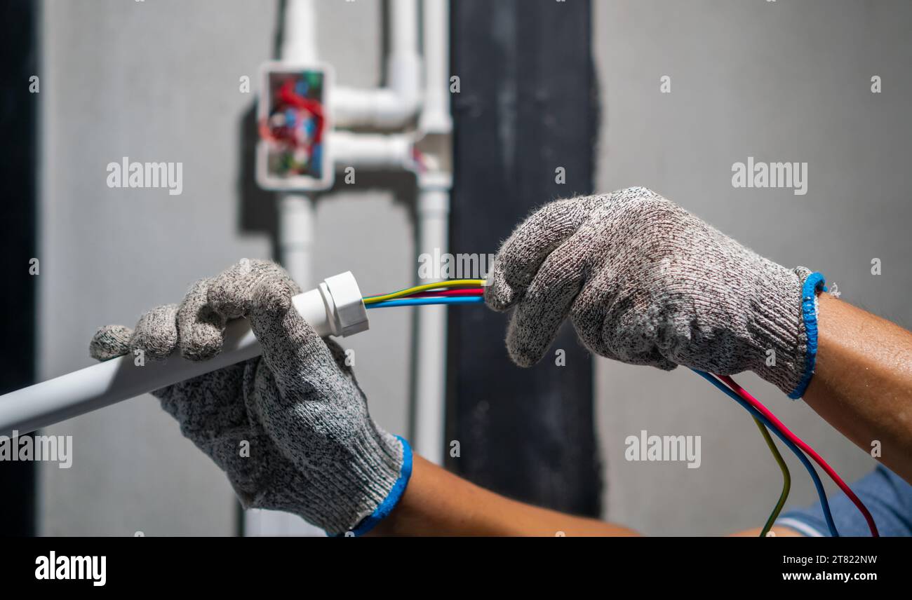 Electrician pulling wire into PVC Conduit. Stock Photo