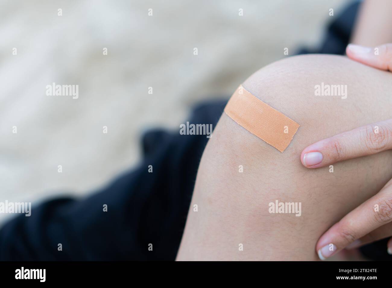 Woman applying plaster on knee Stock Photo