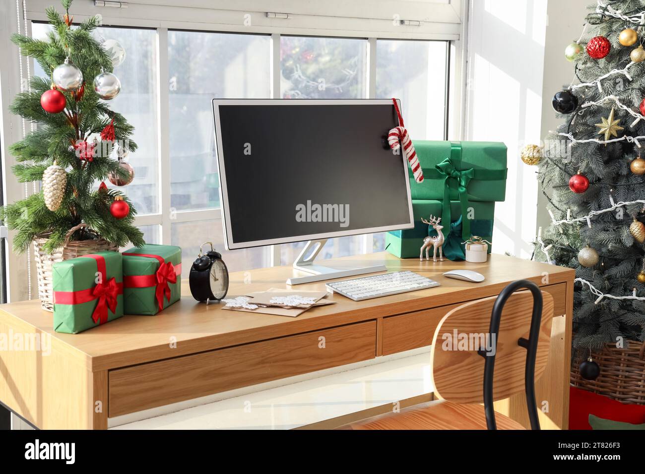 Workplace with computer monitor, presents and Christmas tree in office ...