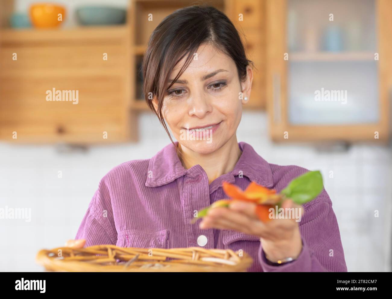 Woman in the kitchen disposes of organic waste in basket Environmental