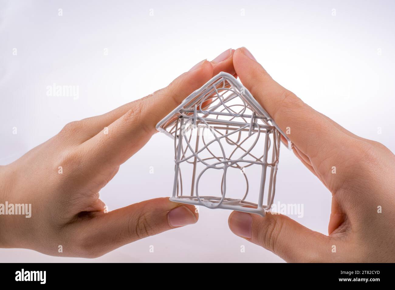 Little model house made of white metal wire in hand Stock Photo