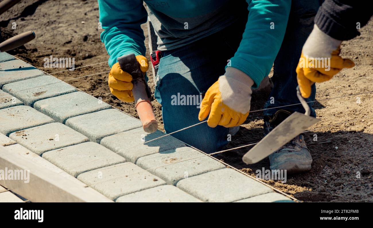 Cobblestone installation, paver laying granite stone pavers using industrial cobblestones Stock Photo