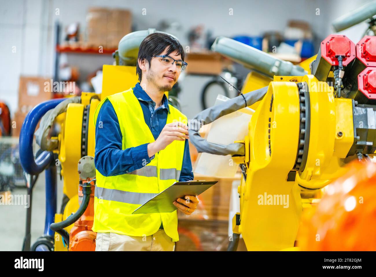 Japanese young engineer controlling the production line of robotic arms Stock Photo