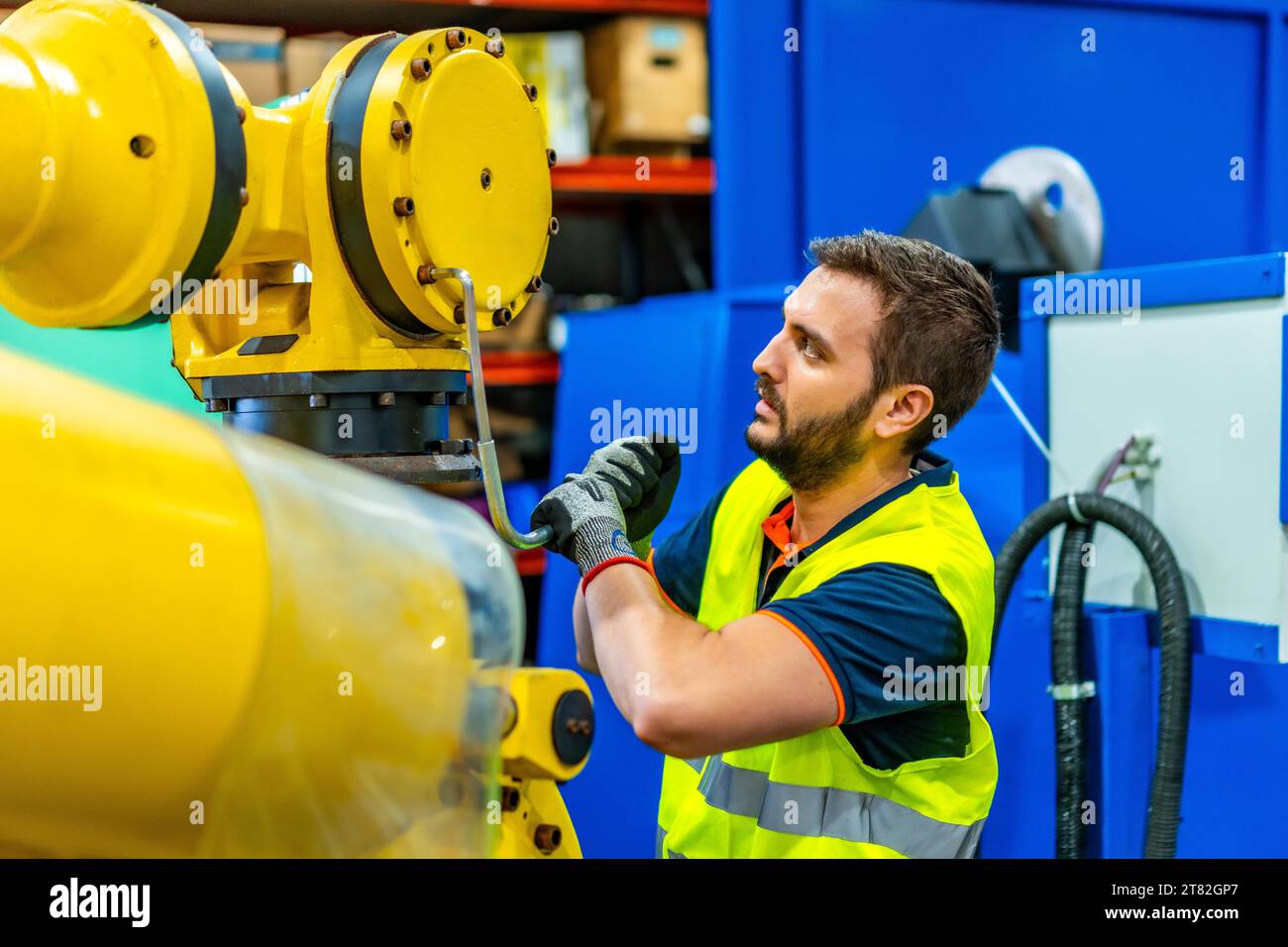 Mechanic repairing a piece of a robotic arm in an assembly line Stock Photo