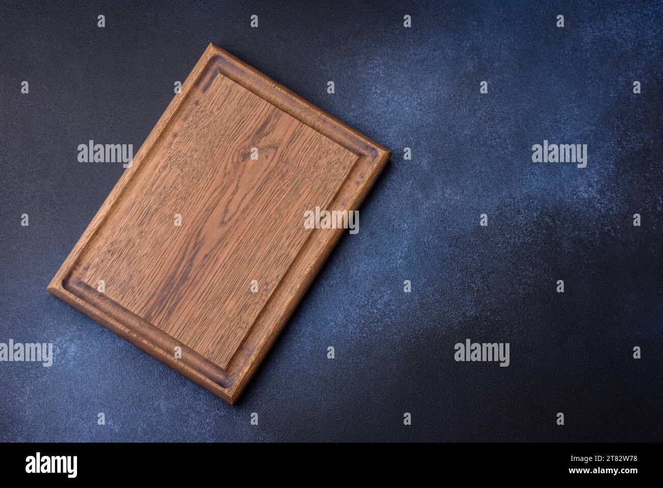 Empty rectangular wooden cutting board on dark concrete background. Cooking at home Stock Photo