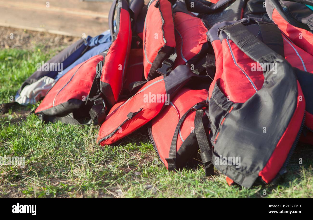 Life jackets piled up on the grass. Active tourism at freshwaters coasts concept Stock Photo