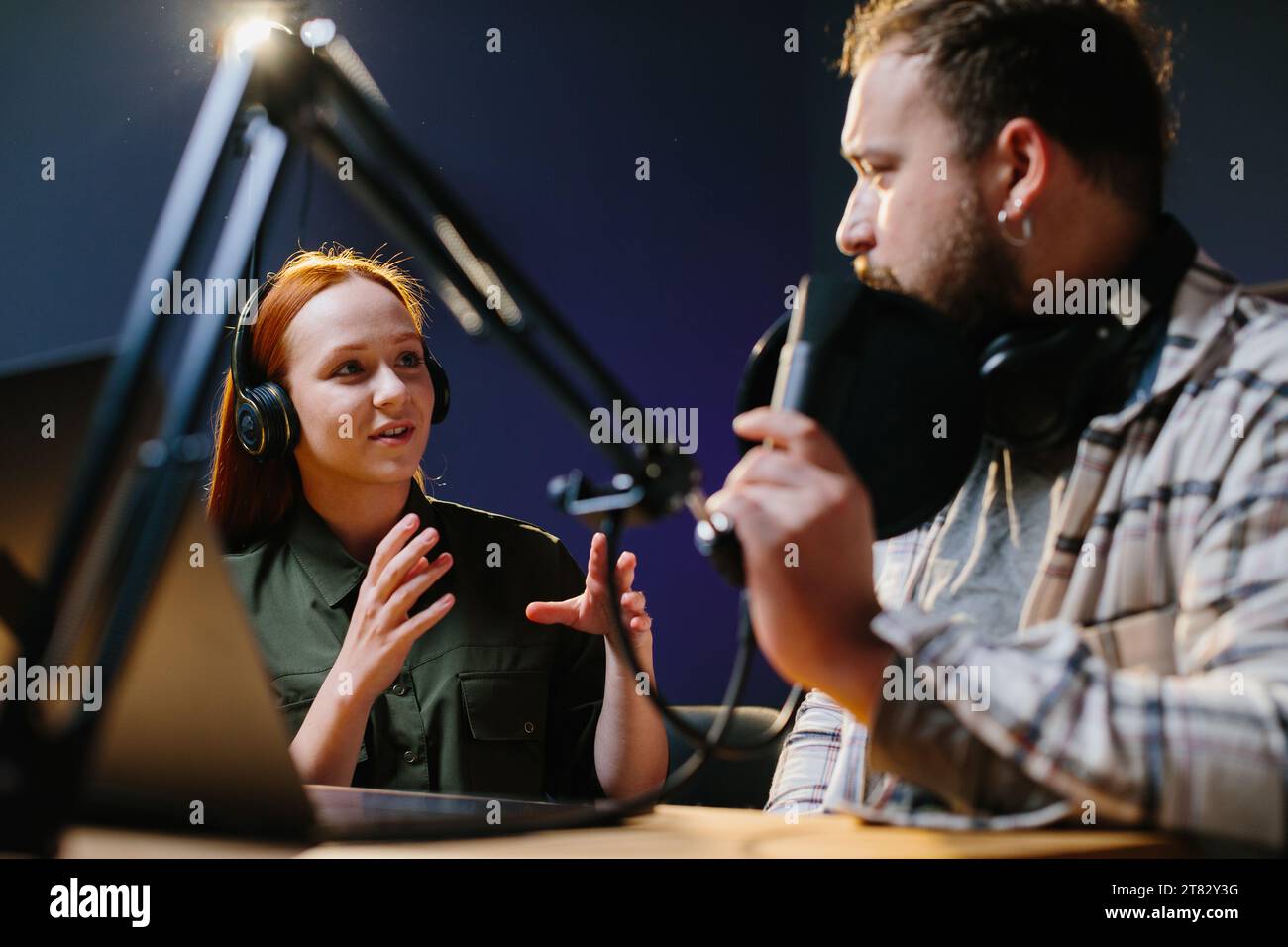 Man having conversation with woman in internet broadcast using professional microphone and audio mixer. Online radio station host recording podcast in Stock Photo