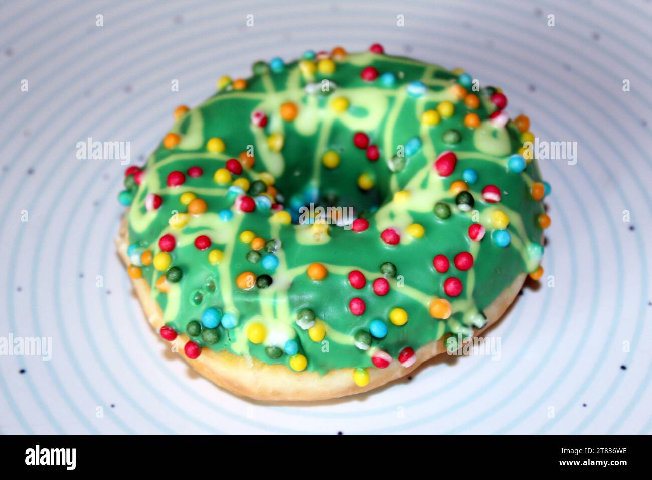 One green glazed doughnut isolated on blue circles plate Stock Photo