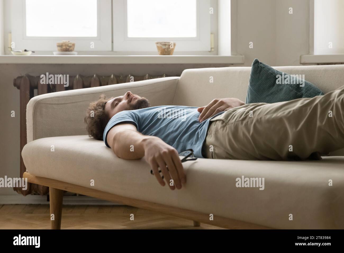 Tired young man having daytime nap on sofa at home Stock Photo