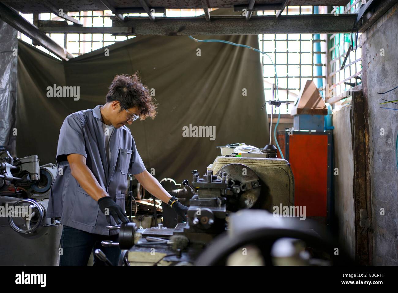 Trainee works at machine shop. Metalwork and education concept. Stock Photo