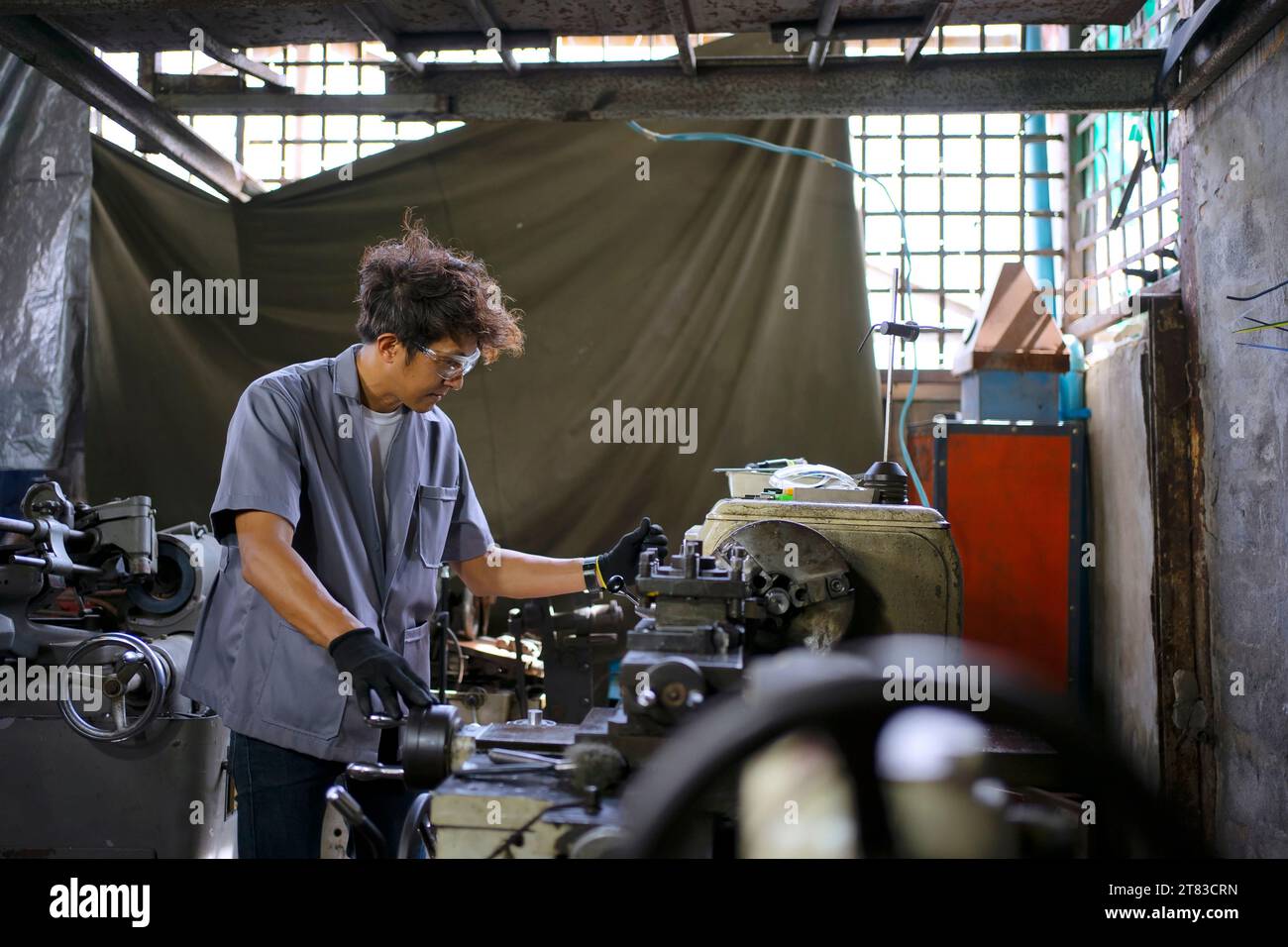 Trainee works at machine shop. Metalwork and education concept. Stock Photo