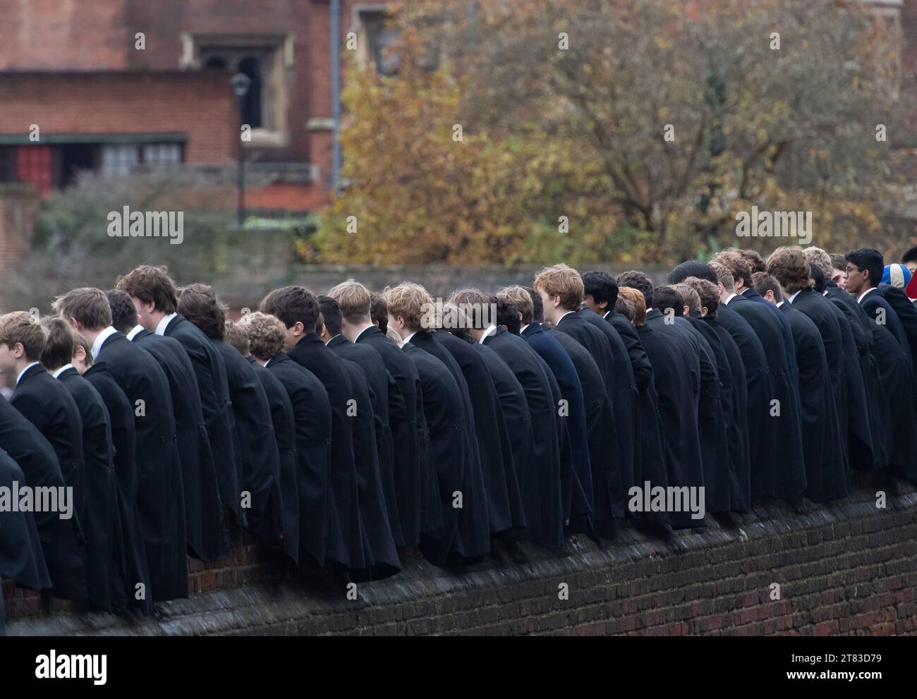 Eton, Windsor, Berkshire, UK. 18th November, 2023. It was a busy day today in Eton for the famous annual Eton College Wall Game. The game originated at, and is still played at Eton College. It is celebrated each year on St Andrew's Day. Eton College boys climb up onto the historic wall next to the Eton College playing fields to watch the game and cheer on the players. The Wall Game is played on a strip of ground 5 metres wide and 110 metres long next to a slightly curved brick wall that was erected in 1717. It is one of two codes of football played at Eton, the other being the Eton Field Game. Stock Photo