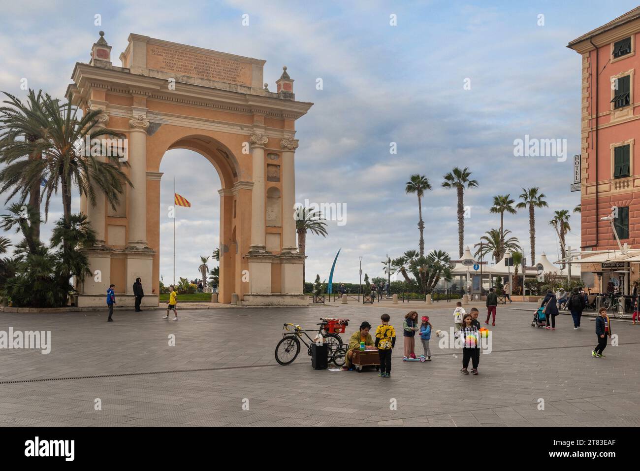 Piazza Vittorio Emanuele II with the triumphal arch to Margaret of Spain (1666) and playing children, Finale Ligure, Savona, Liguria, Italy Stock Photo