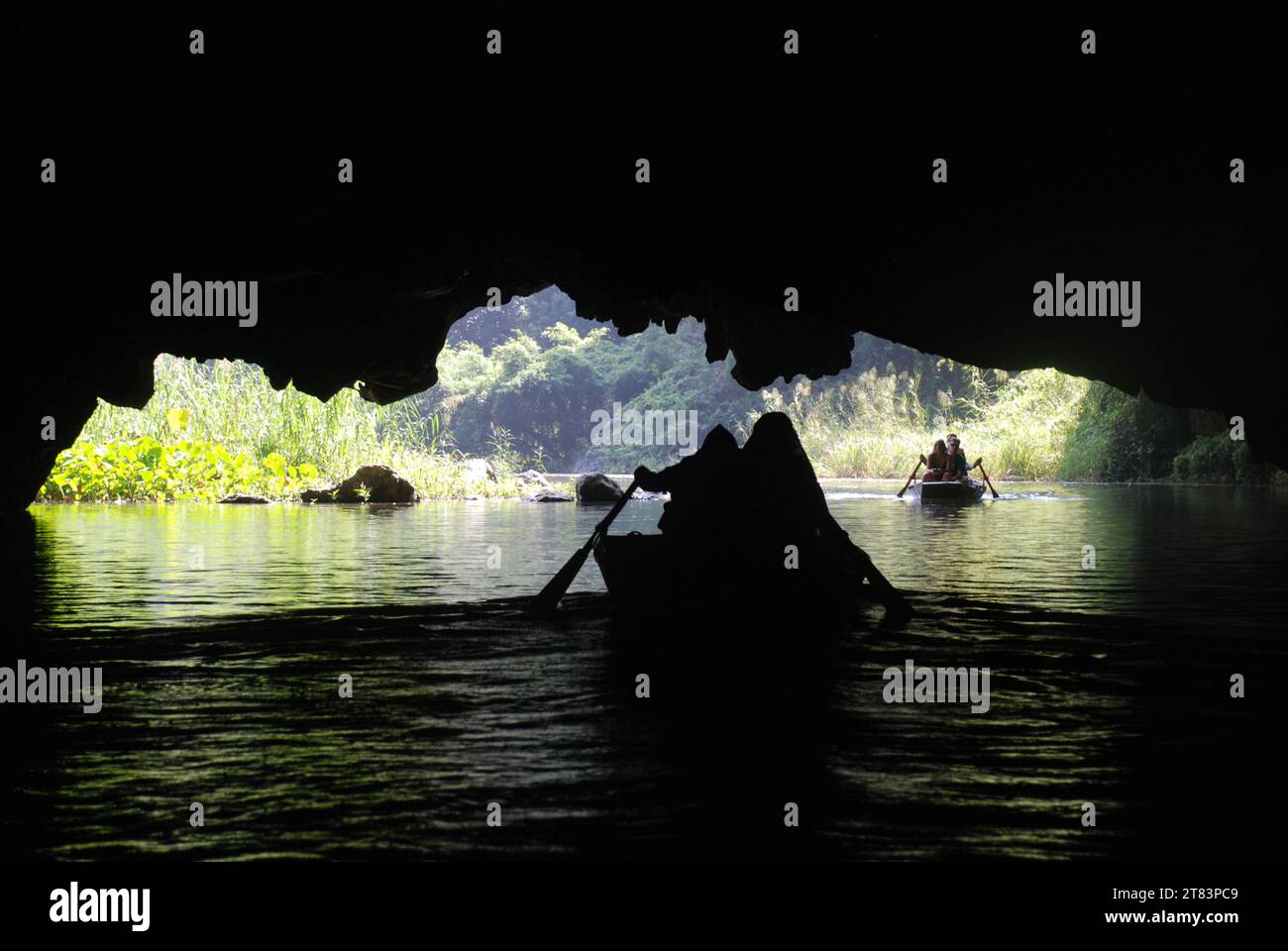 tourists ride in traditional Vietnamese rowing boats  amongst the limestone cliffs and caves at Tam Coc Stock Photo