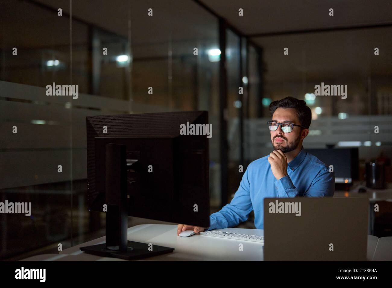 Busy business man software developer using computer working late in office. Stock Photo