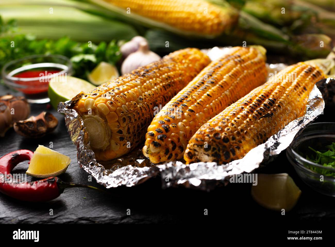 Grilled corn on the cob in tin foil on kitchen table healthy gluten free food background Stock Photo