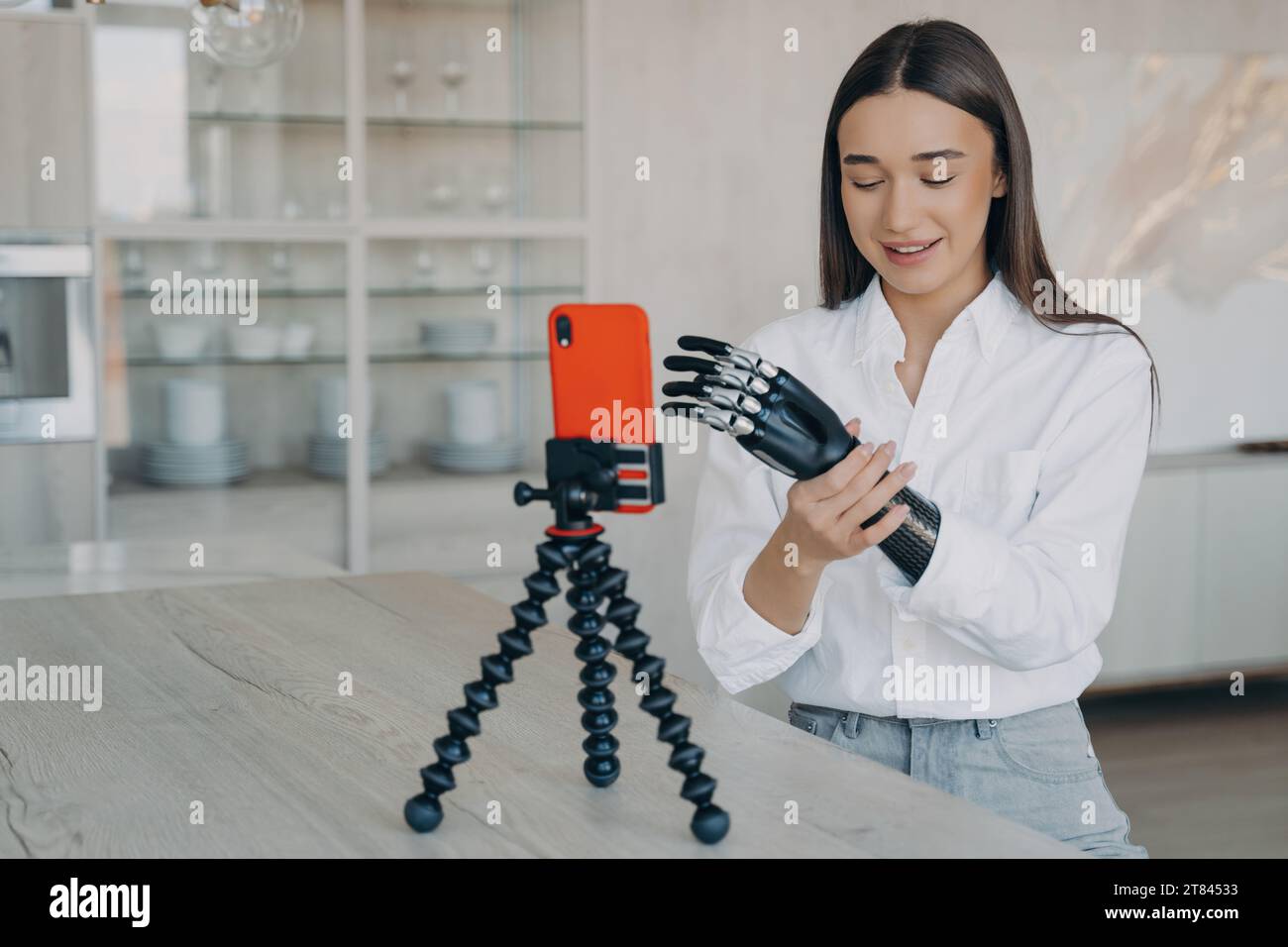 Joyful woman with a bionic arm filming a vlog, showcasing the seamless blend of daily life and advanced tech Stock Photo