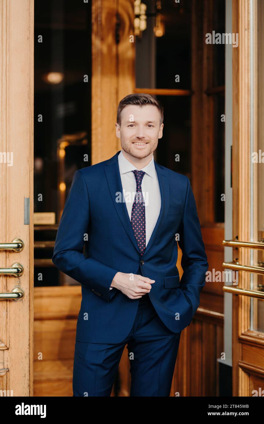Smartly dressed man in a tailored blue suit and tie standing ...