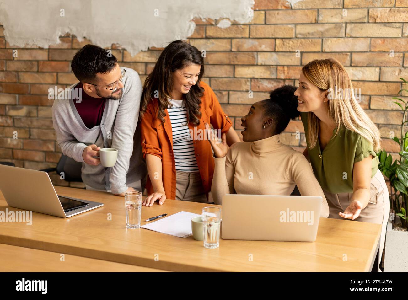 Young multiethnic startup team working by the brick wall in industrial style office Stock Photo