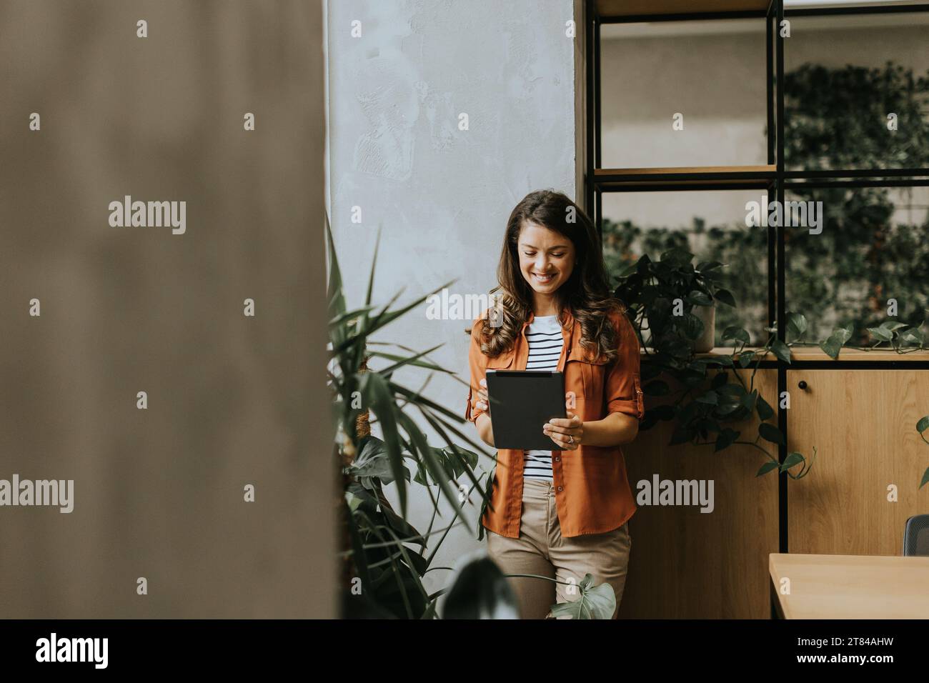Pretty young woman standing with digital tablet at the office Stock Photo
