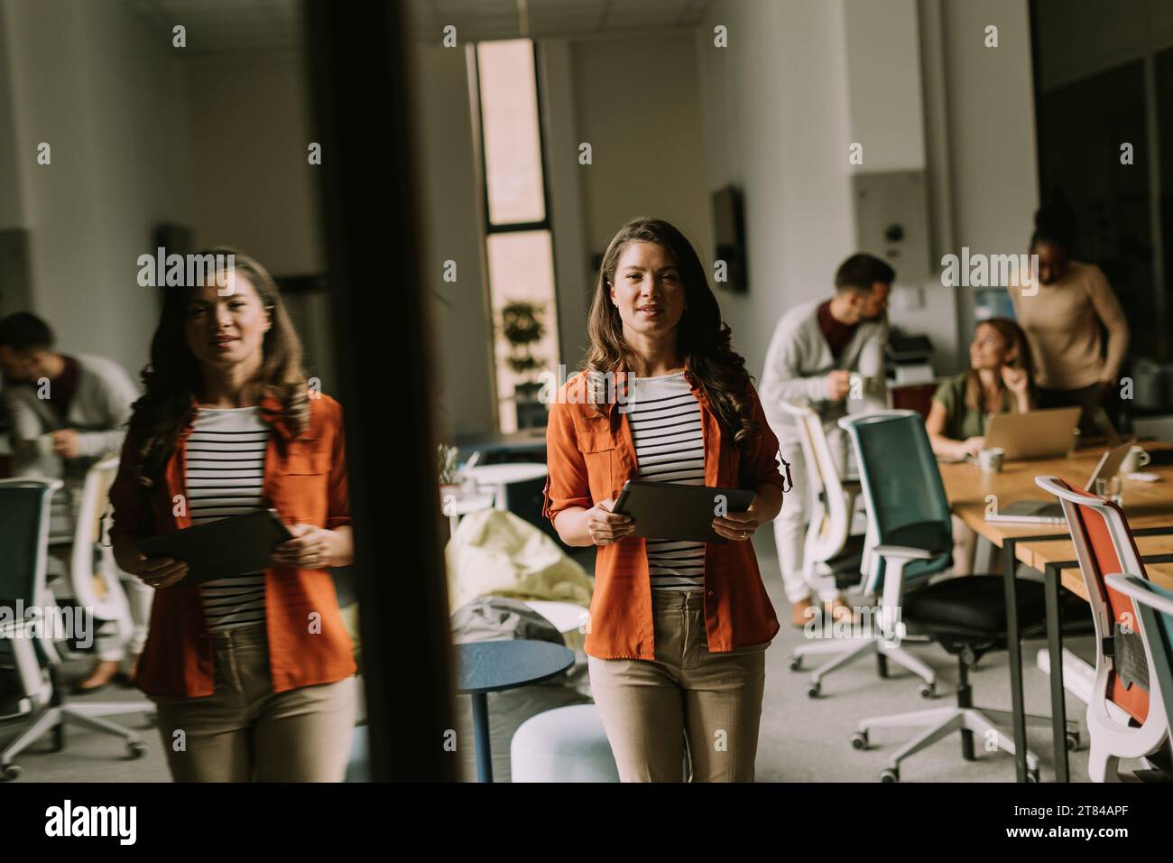 Young woman standing with digital tablet in front of her team at the modern office Stock Photo