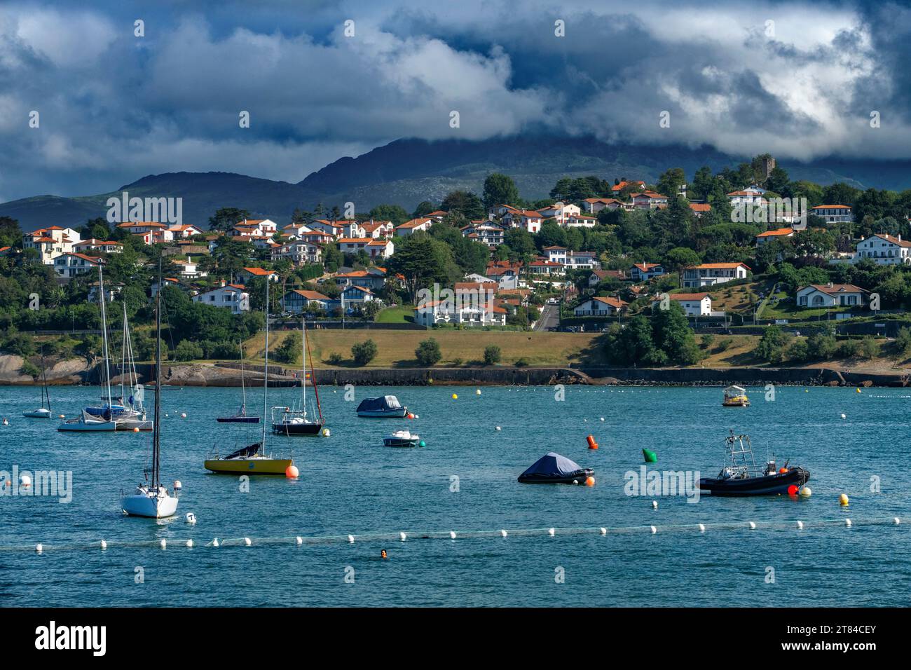 The Rhune mountain overlooking Ciboure Basque country. France Small coloreful fish boats on the old port of cituadel in front of Saint Jean de luz. Stock Photo