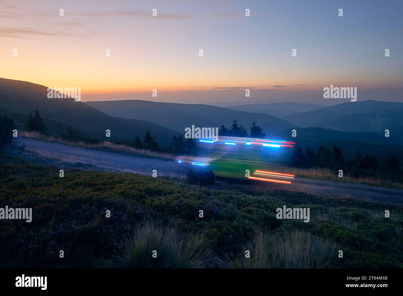 Light trails of ambulance car of emergency medical service on mountain road at night. Themes healthcare, rescue and urgency. Stock Photo