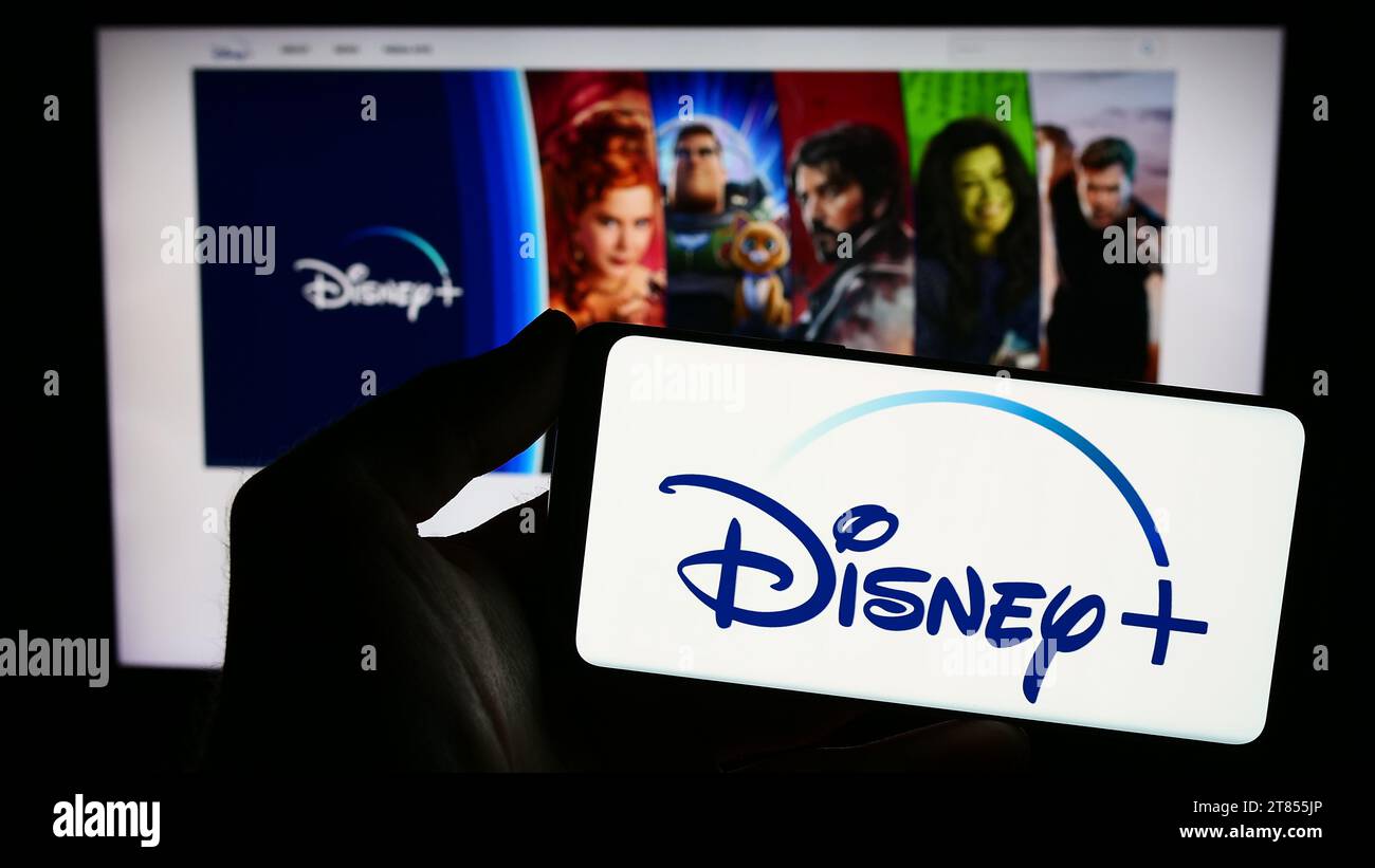 Person holding smartphone with logo of US video-on-demand streaming service Disney Plus in front of website. Focus on phone display. Stock Photo
