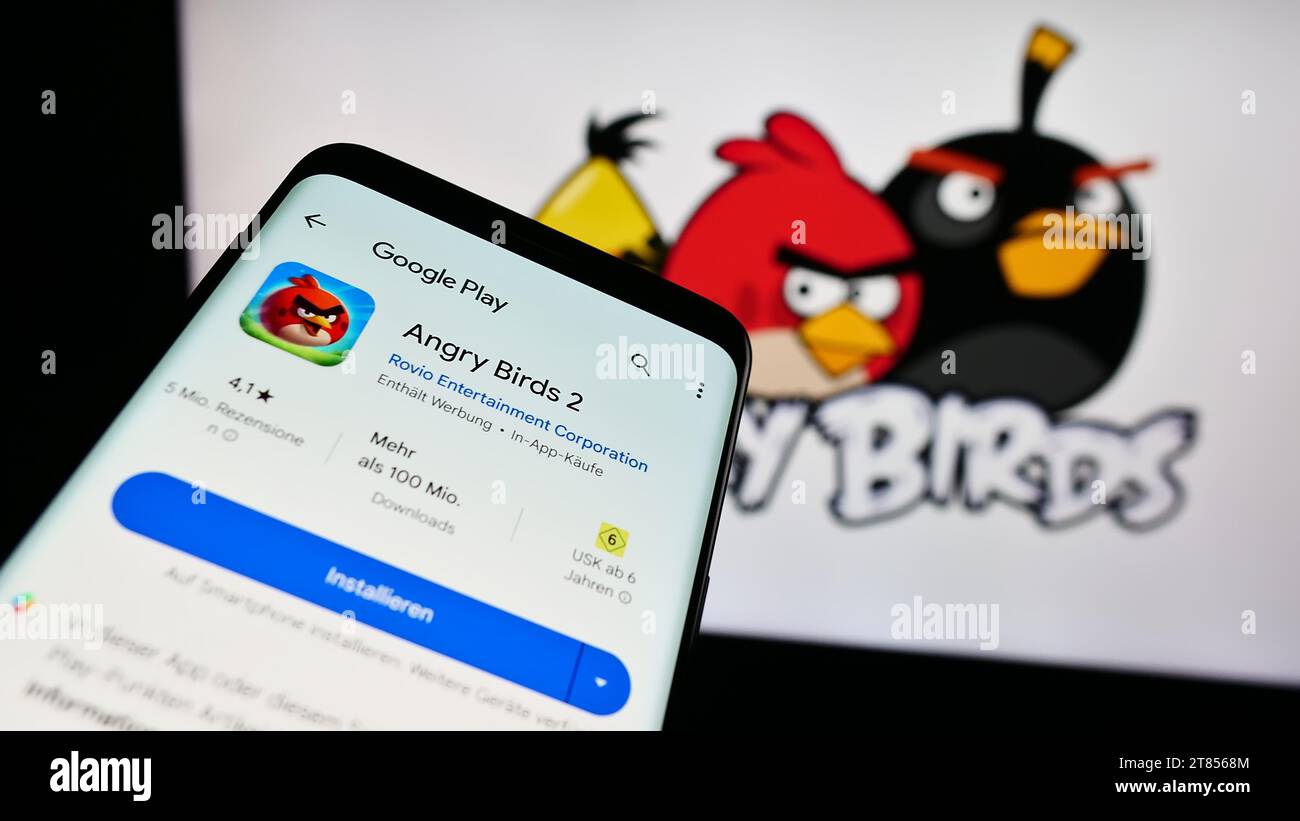 Mobile phone with website of artillery video game Angry Birds in front of company logo. Focus on top-left of phone display. Stock Photo