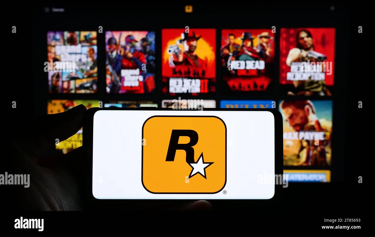 Person holding smartphone with logo of US video game publishing company Rockstar Games Inc. in front of website. Focus on phone display. Stock Photo