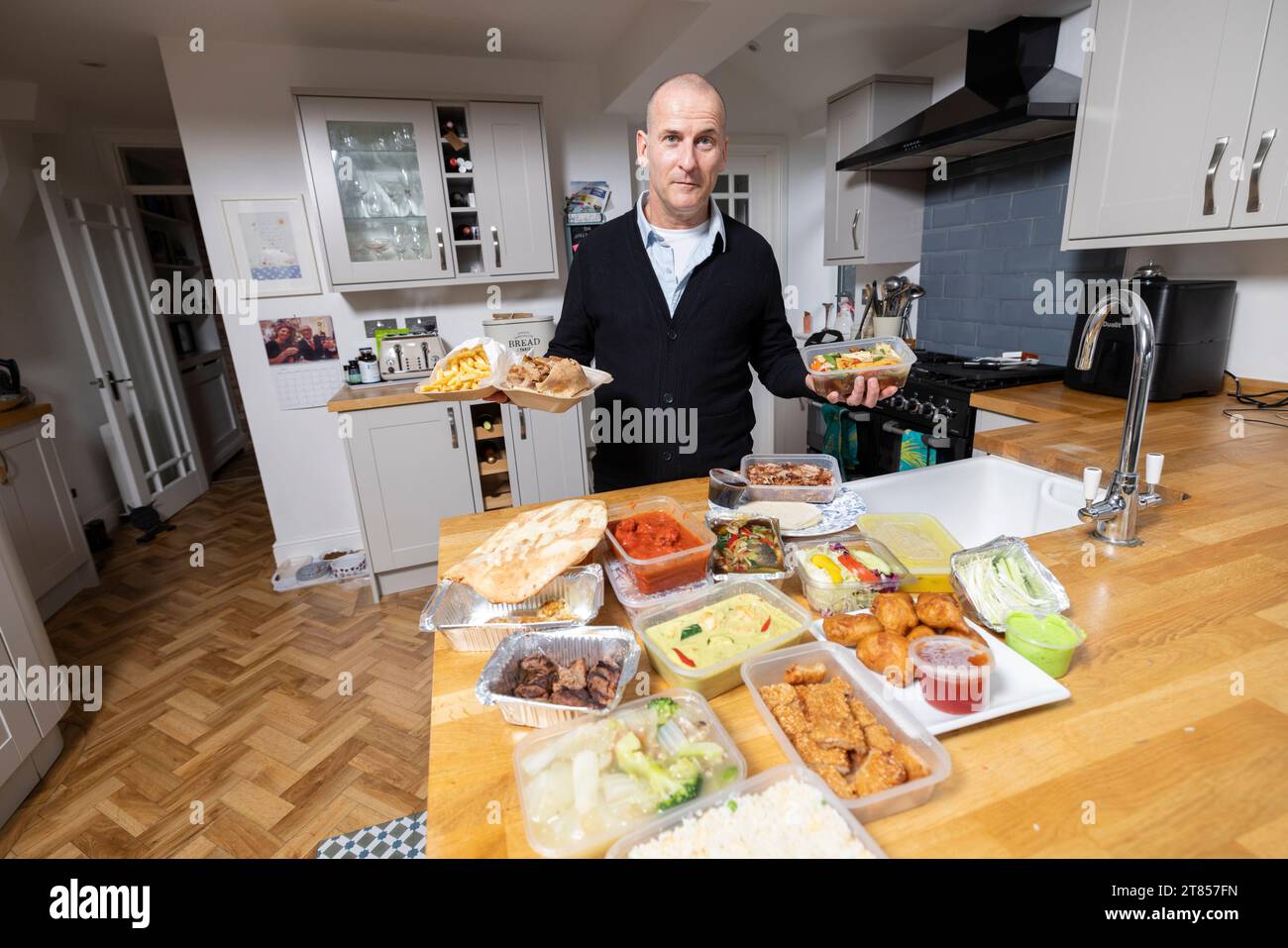 Man at home with section of take-away food on his kitchen work top, London, England, United Kingdom Stock Photo