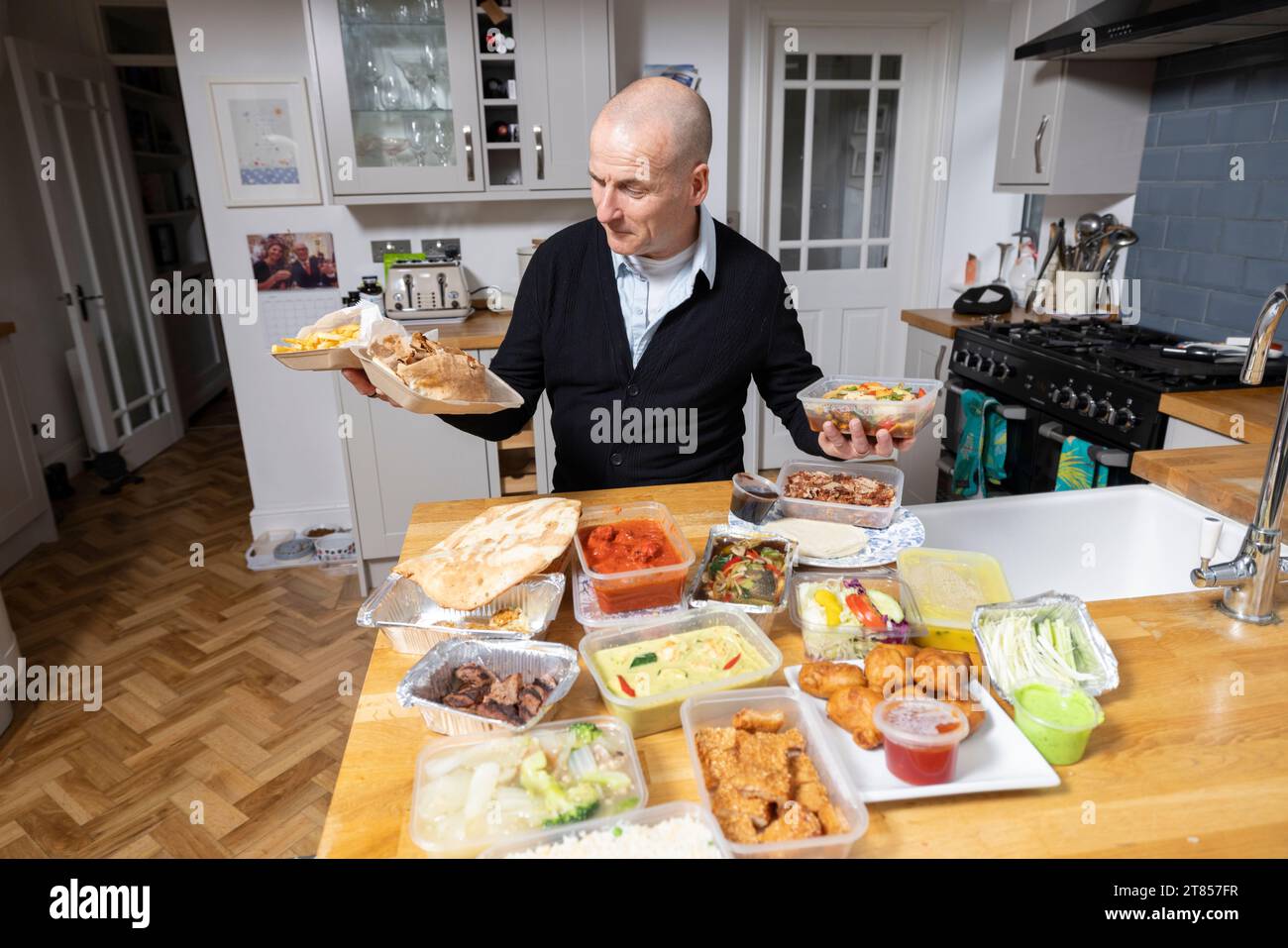 Man at home with section of take-away food on his kitchen work top, London, England, United Kingdom Stock Photo
