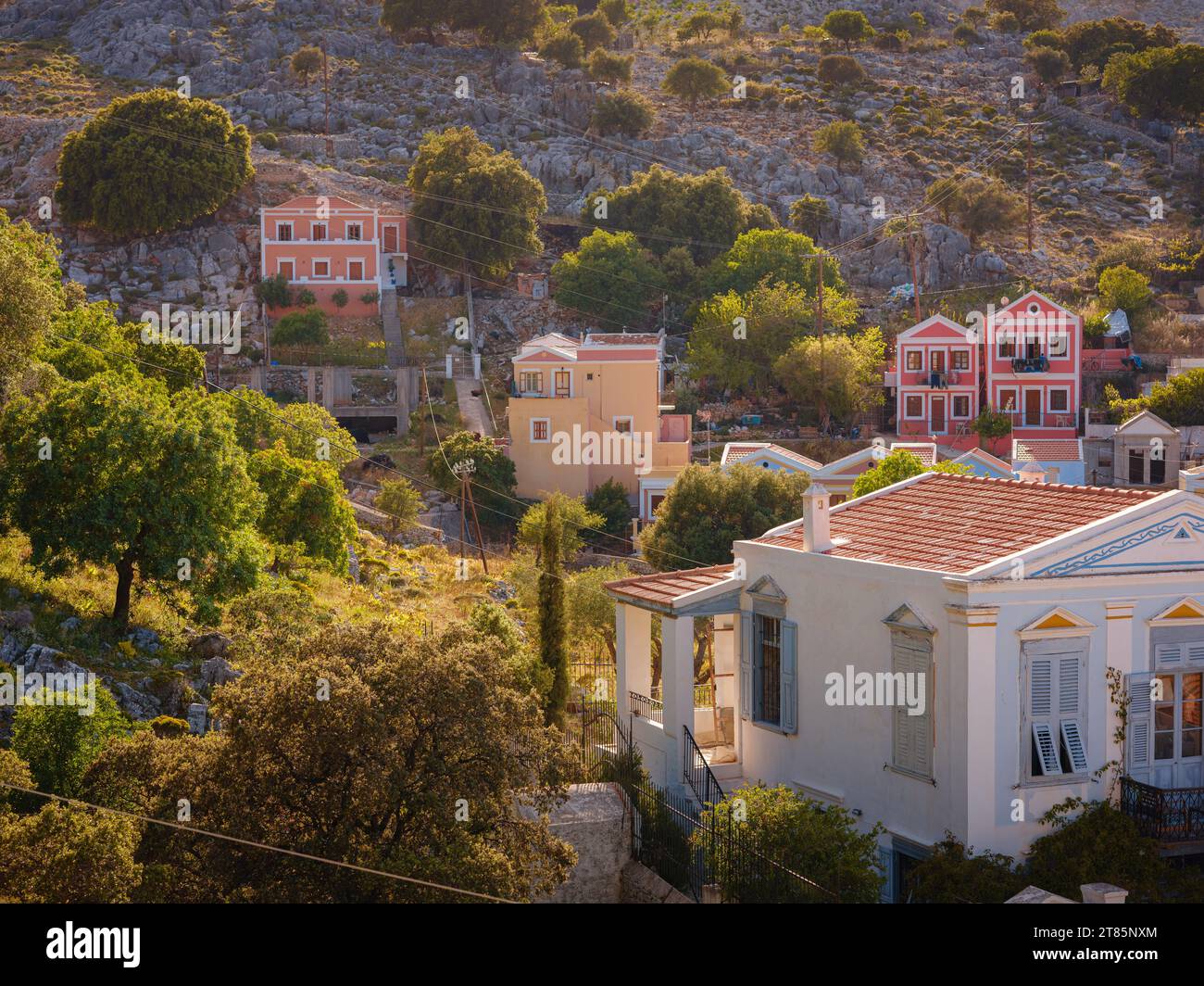 Symi Island, Greece. Greece islands holidays from Rhodos in Aegean Sea. Colorful neoclassical beautiful houses on hillsides of a Greek island during sunset. Holiday travel background. Stock Photo