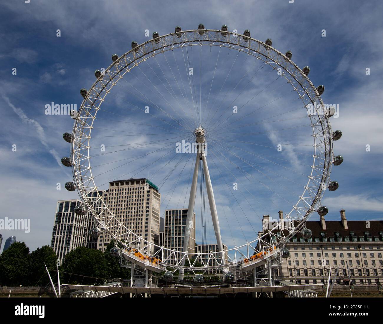 Wide-angle shot of London Eye ferris wheel with passenger capsules against a cloudy sky Stock Photo