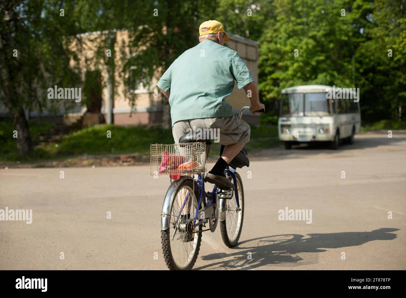 Elderly man on bicycle. Old man rides bicycle. Man in town. Pensioner rides down street. Stock Photo