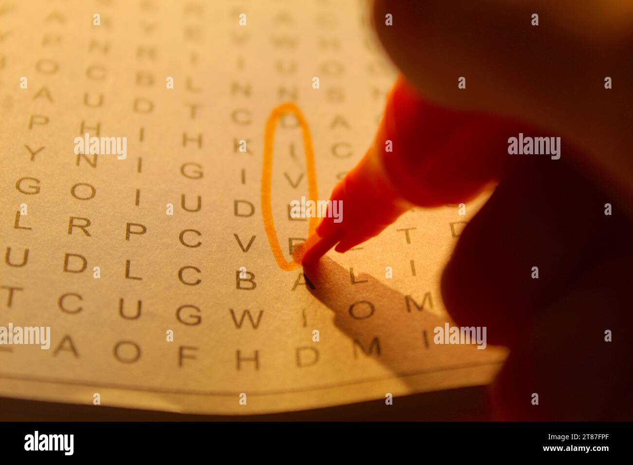A photo of someone completing a crossword puzzle with an orange marker