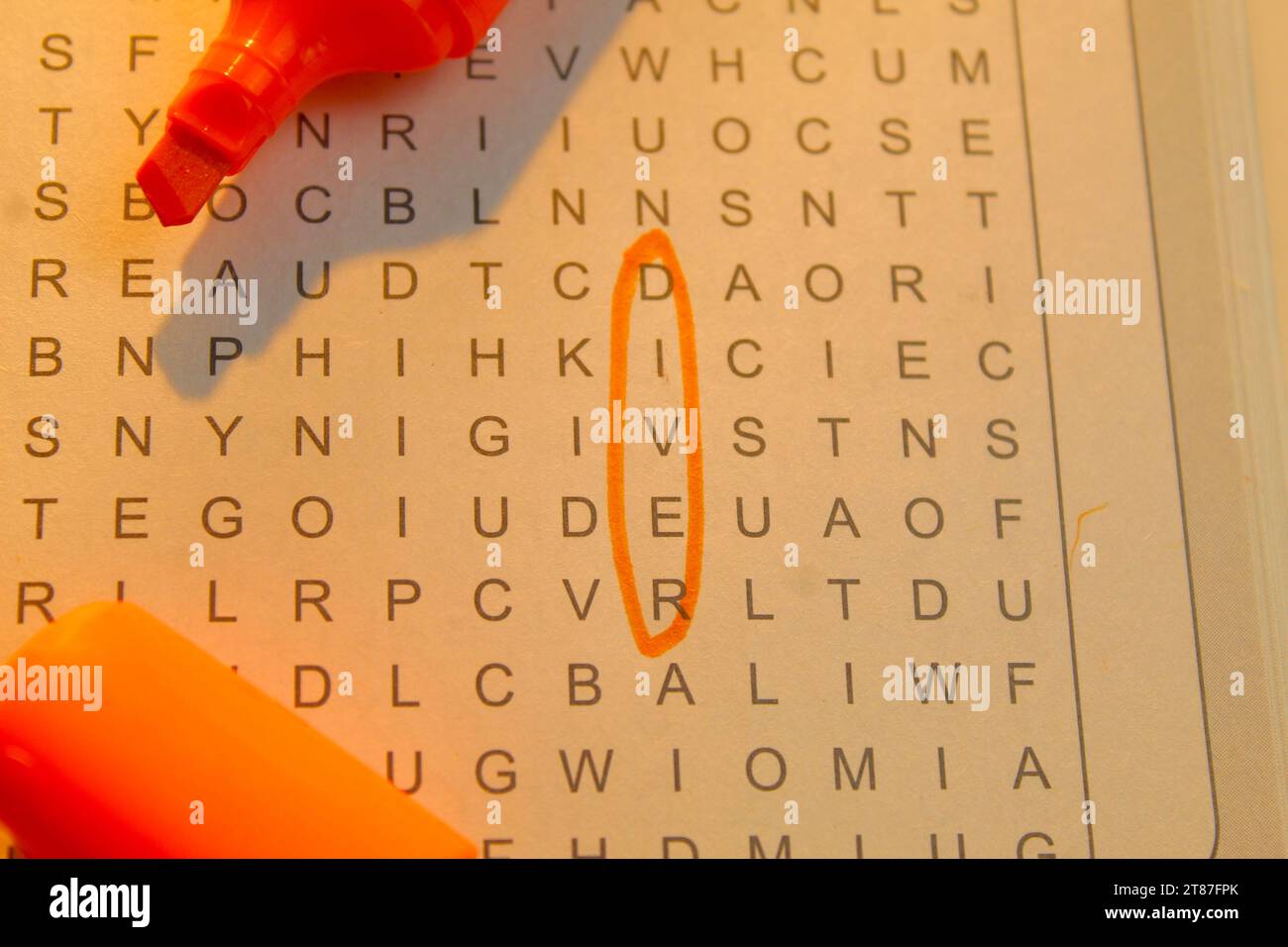 A photo of someone completing a crossword puzzle with an orange marker
