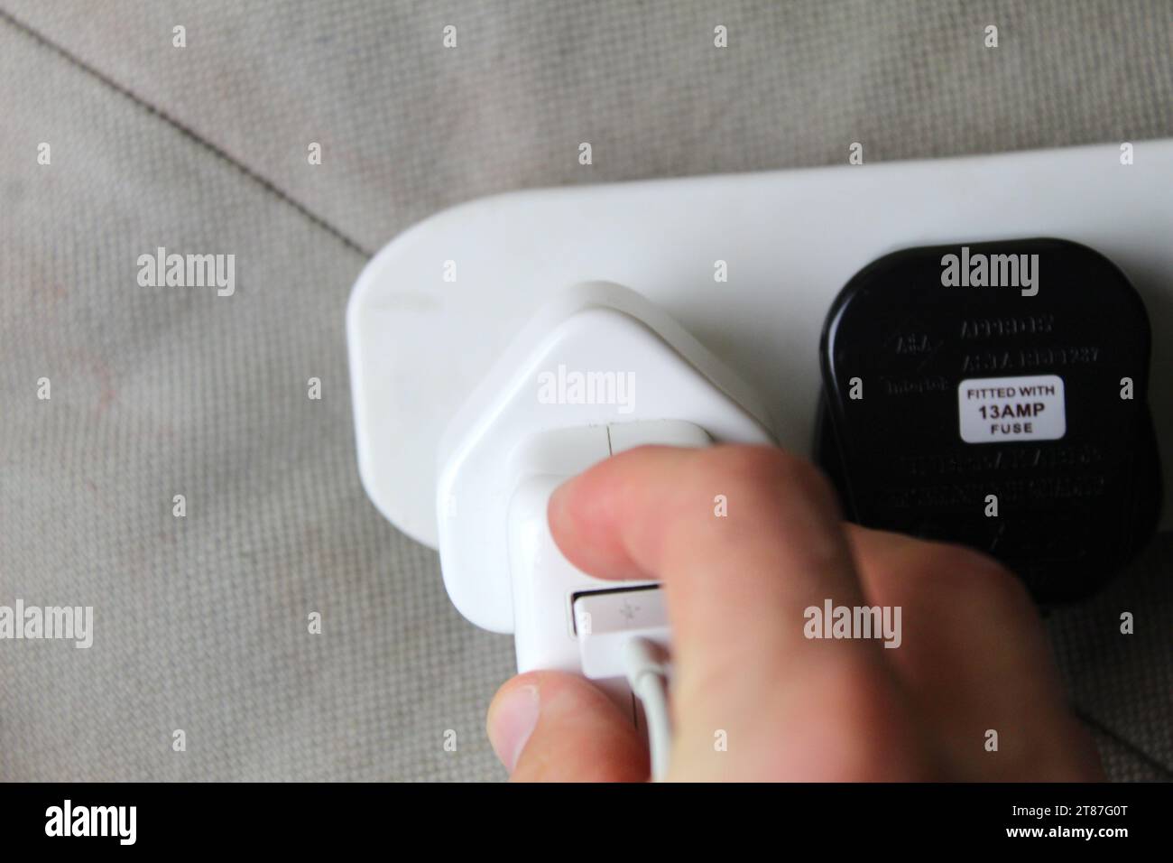 A photo of someone plugging in an electrical smartphone charger plug