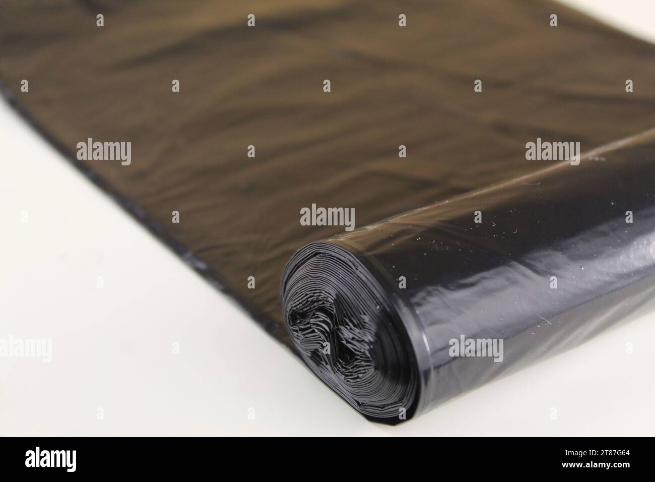 A photo of a black bin liner rolled out over a white surface. Stock Photo