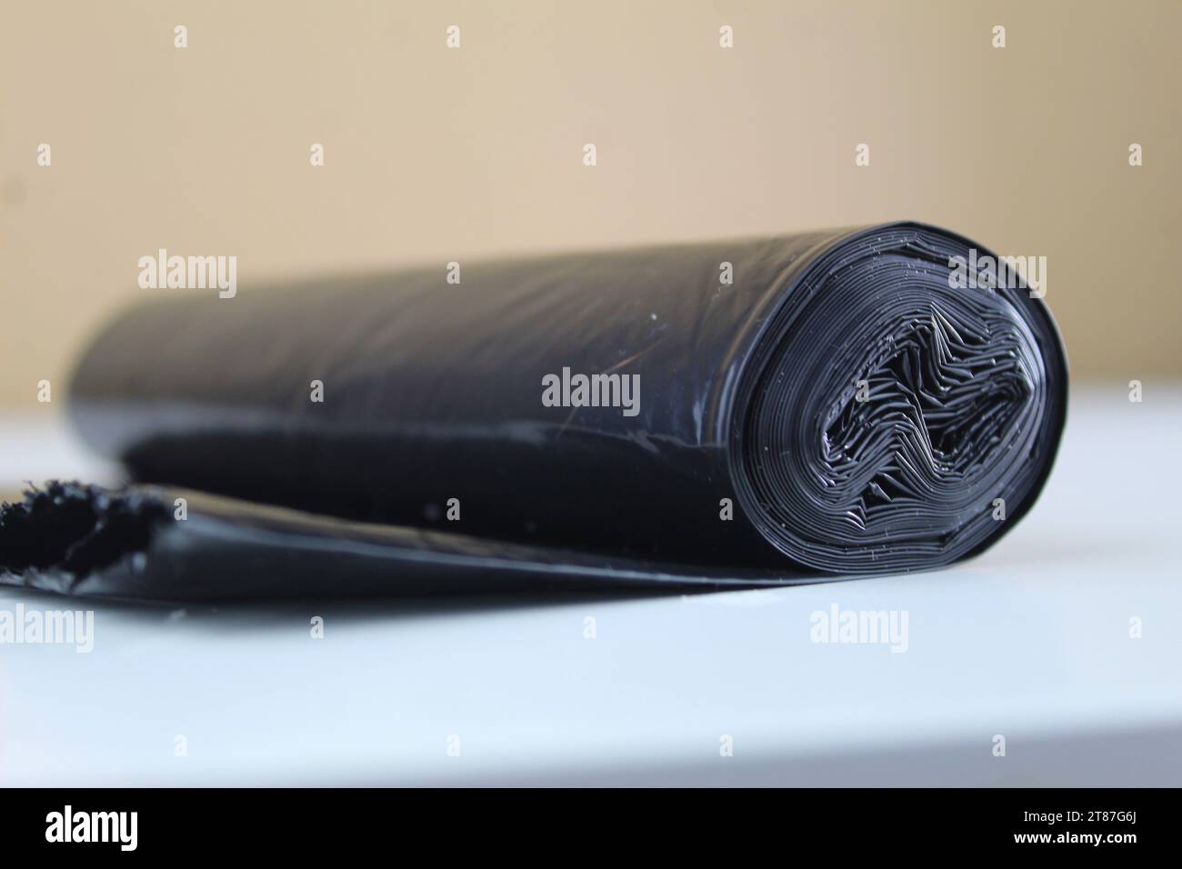 A photo of a black bin liner rolled out over a white surface Stock