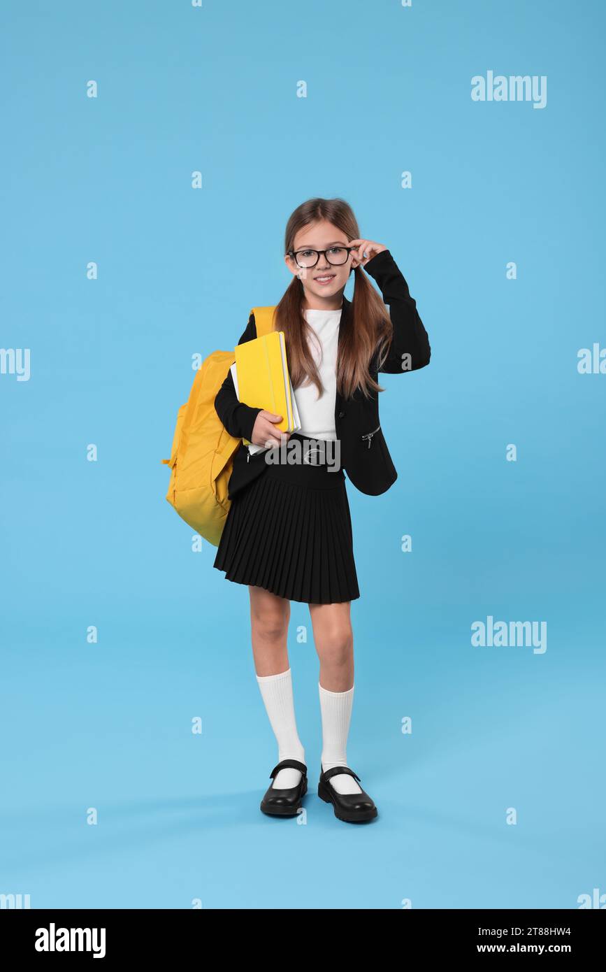 Happy schoolgirl with backpack and books on light blue background Stock ...