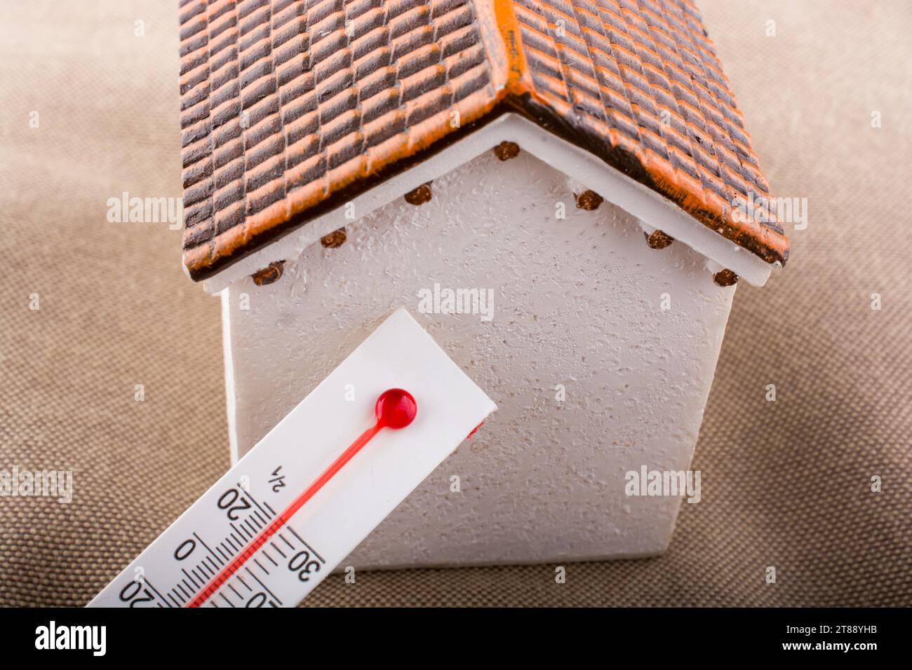 Thermometer measuring temperature by a little model house Stock Photo