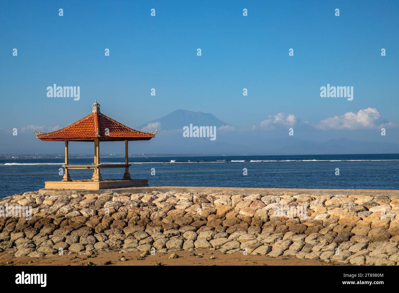 Sanur beach. Temple in the calm sea. Small waves in the morning. Sandy beach on the dream island of Bali. in the background the volcano Mount Agung Stock Photo