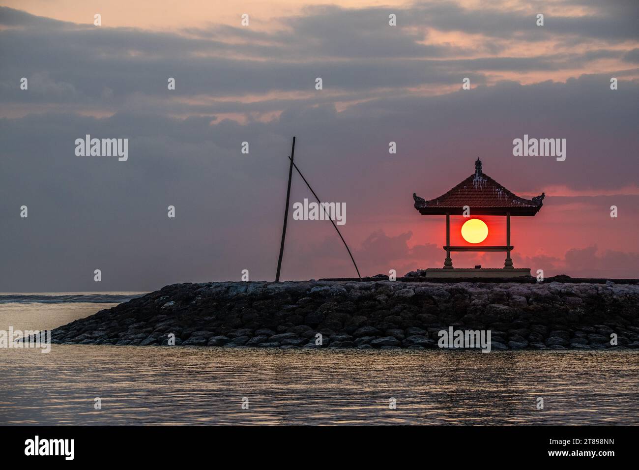 Great sun ball in a small temple in Bali, on the sandy beach of Sanur. Sun ball on the horizon and clouds in the sky. Everything in the morning Stock Photo