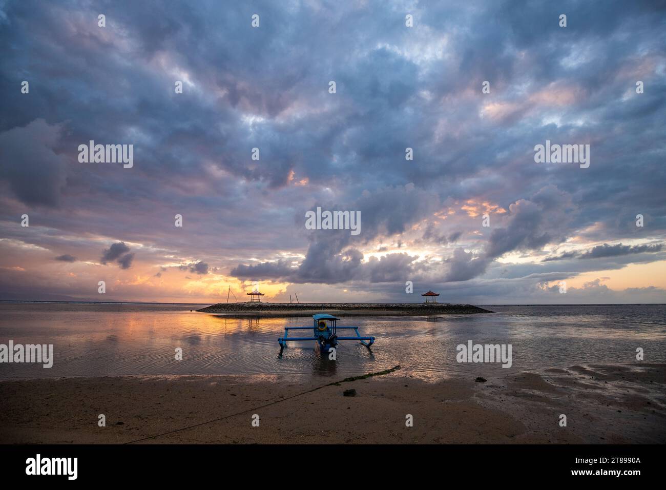 Sunrise at the sandy beach of Sanur. Temple in the water. Traditional fishing boat, Jukung on the beach. Hindu faith in Sanur on Bali. Dream island an Stock Photo