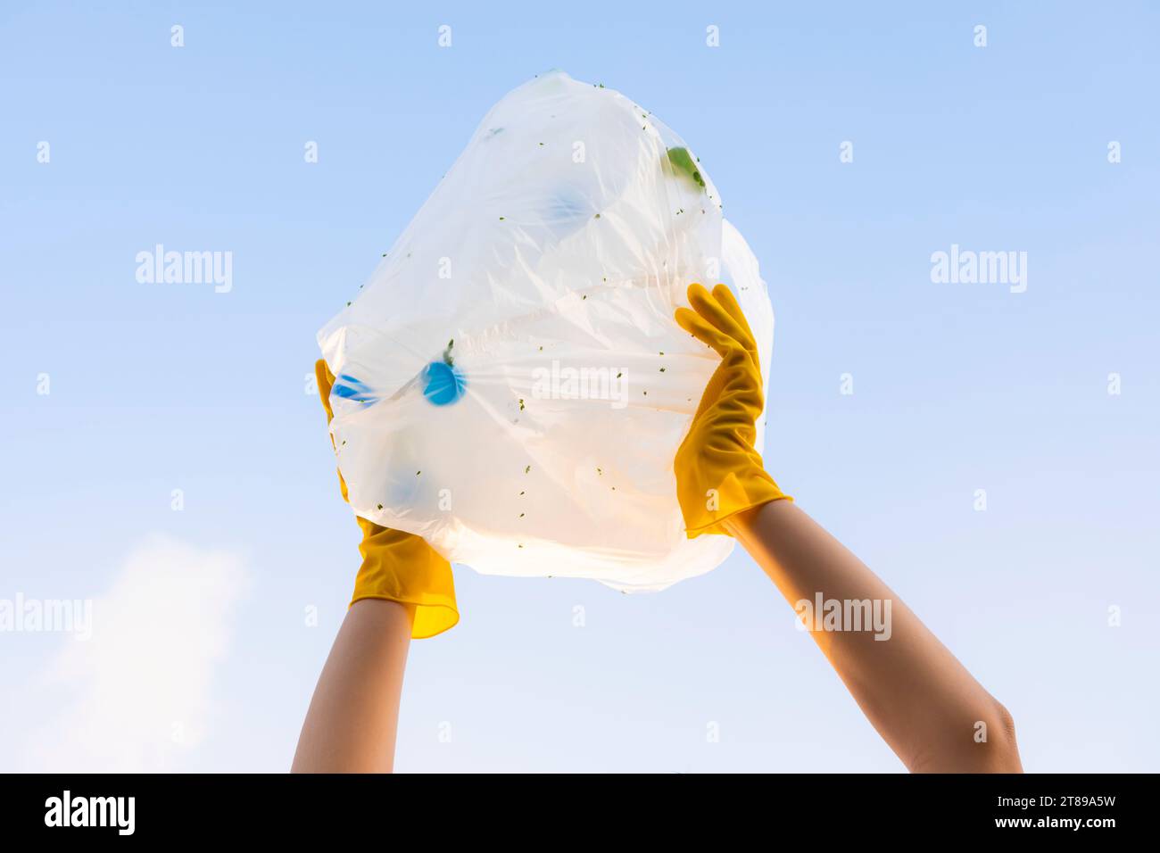 A young volunteer's hand raises a garbage bag of plastic bottles into the sky. On World Environment Day Stock Photo