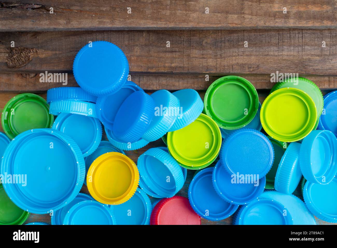 multicolor plastic lids for recycling on a wooden table. Stock Photo