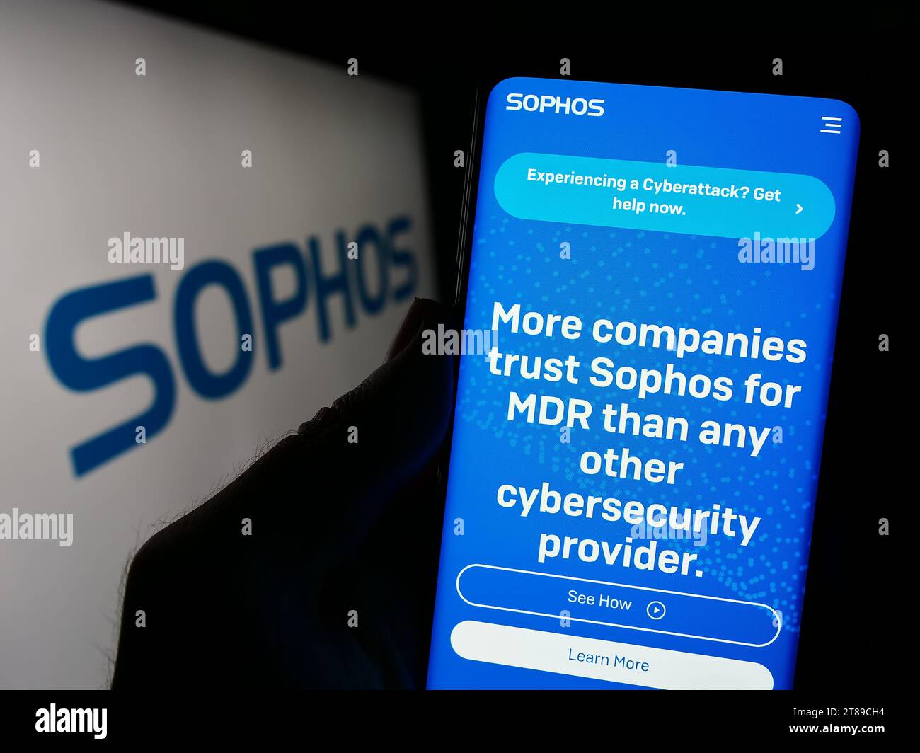 Person holding cellphone with webpage of British security software company Sophos Group plc in front of logo. Focus on center of phone display. Stock Photo