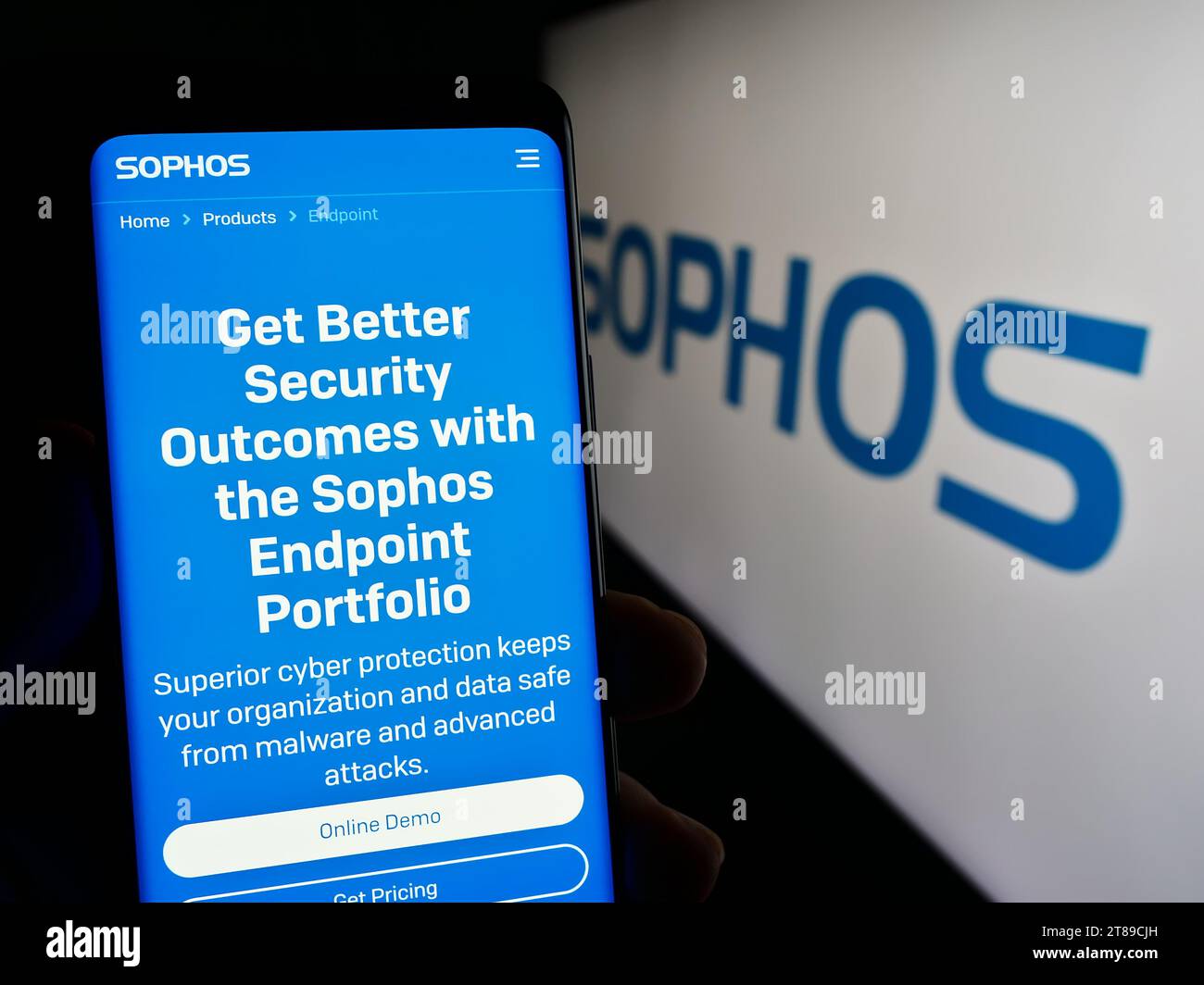 Person holding mobile phone with web page of British security software company Sophos Group plc with logo. Focus on center of phone display. Stock Photo