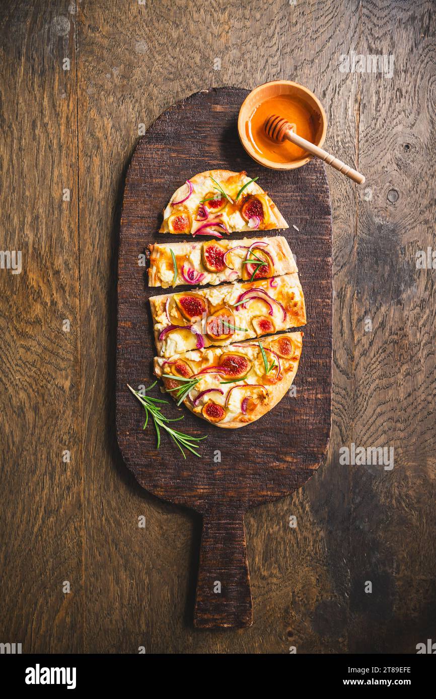 French Tarte Flambee (Flammkuchen) with figs, red onions, soft goat cheese and honey Stock Photo